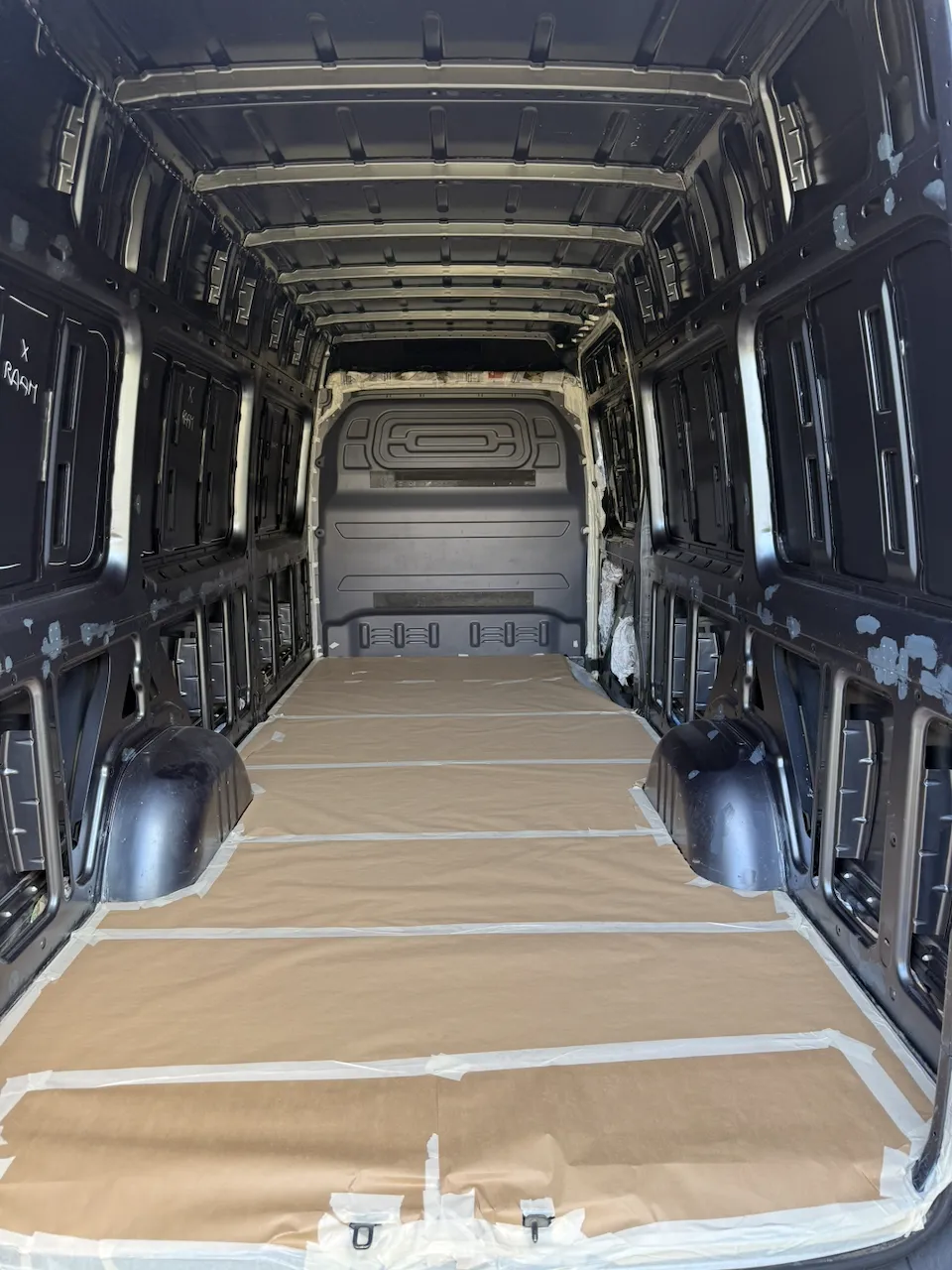 Looking forward through the empty cargo area with the whole floor covered in brown masking paper